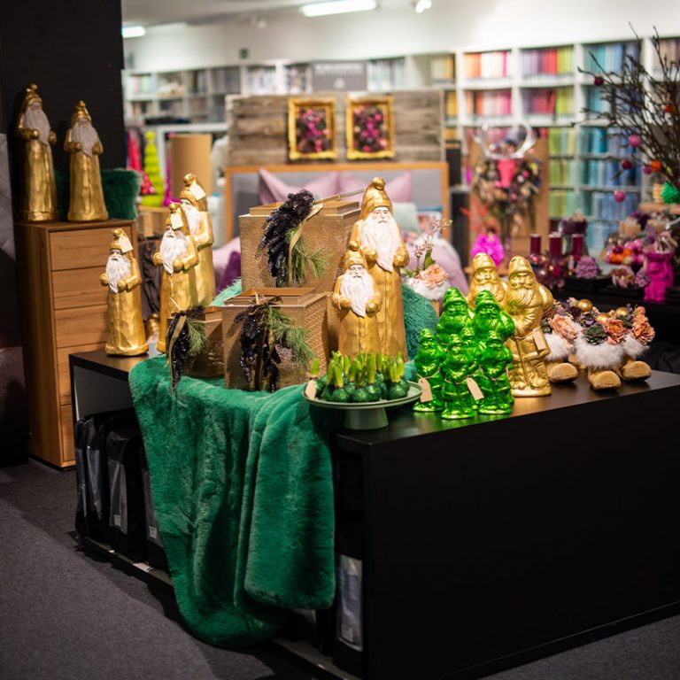 Ladentisch mit goldenen Weihnachtsmannfiguren, grünen Glasbäumchen und Wichteln