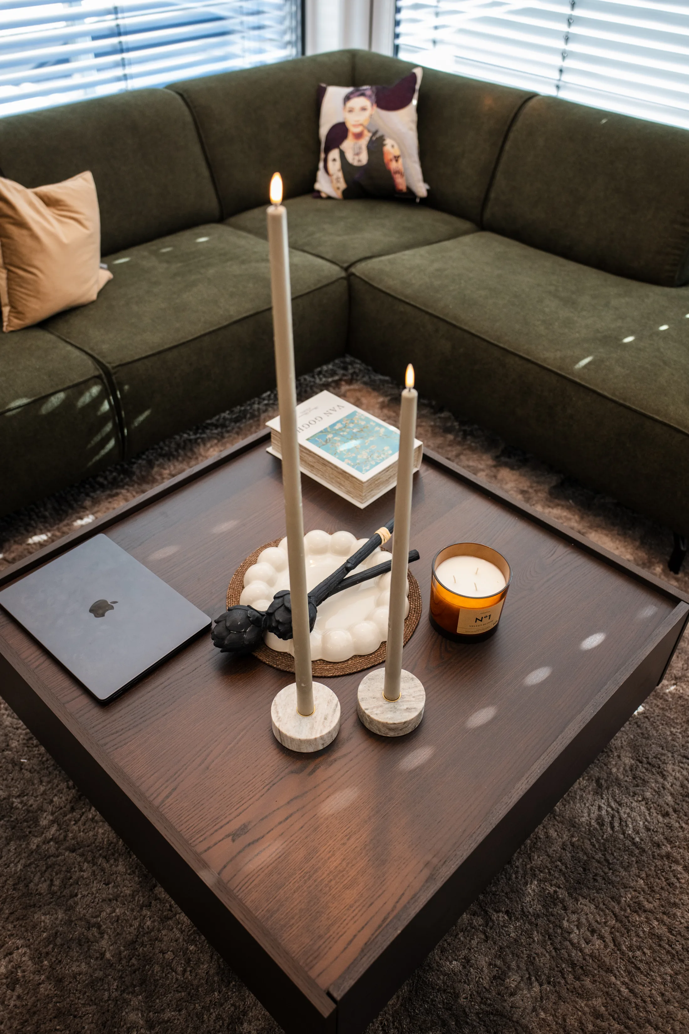Couchtisch mit Spitzkerzen auf Steinhaltern, Duftkerze und Schale vor dem Ecksofa