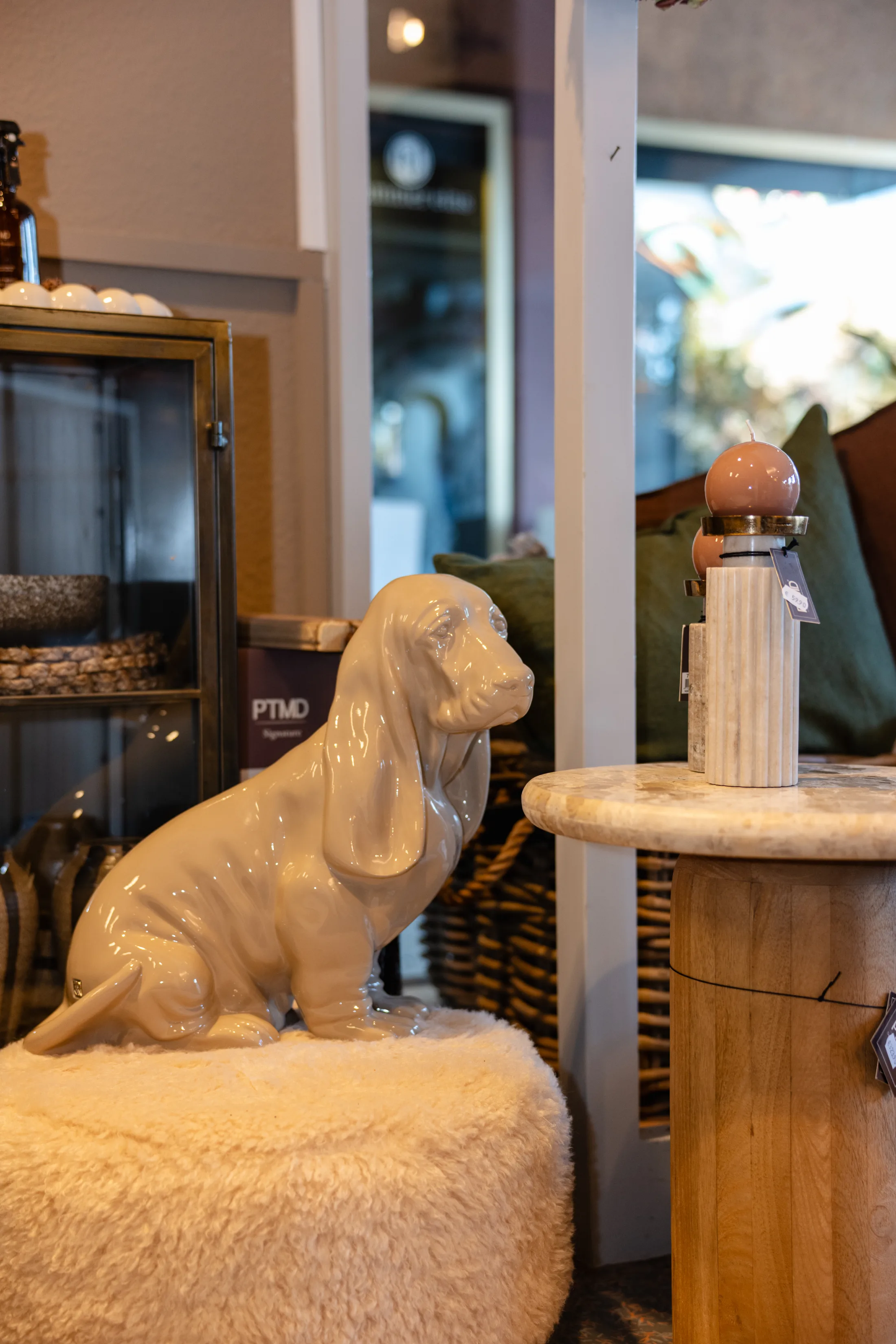 Basset-Figur in Creme auf einem weichen Hocker neben einem Beistelltisch mit Marmorplatte