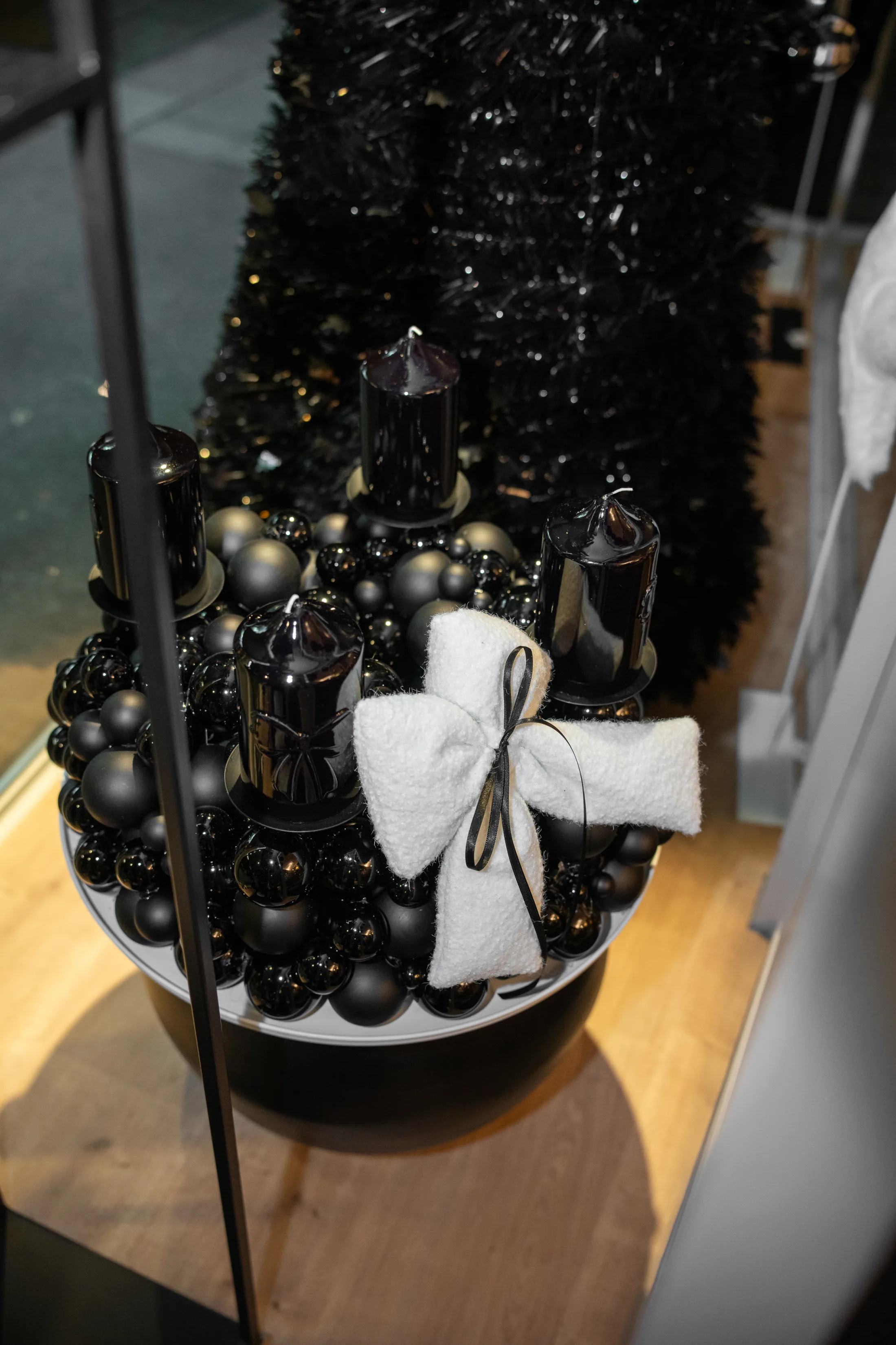 Adventskranz Schwarz im Schaufenster, vor einem schwarzen Tannenbaum