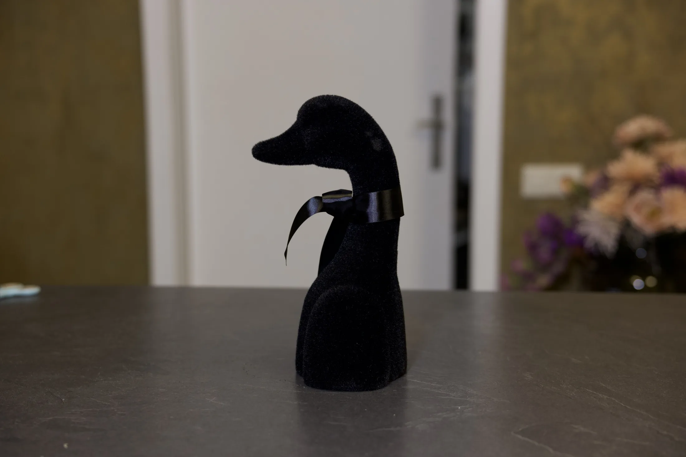 Gans in Schwarz von der Seite, mit Satinschleife am Hals