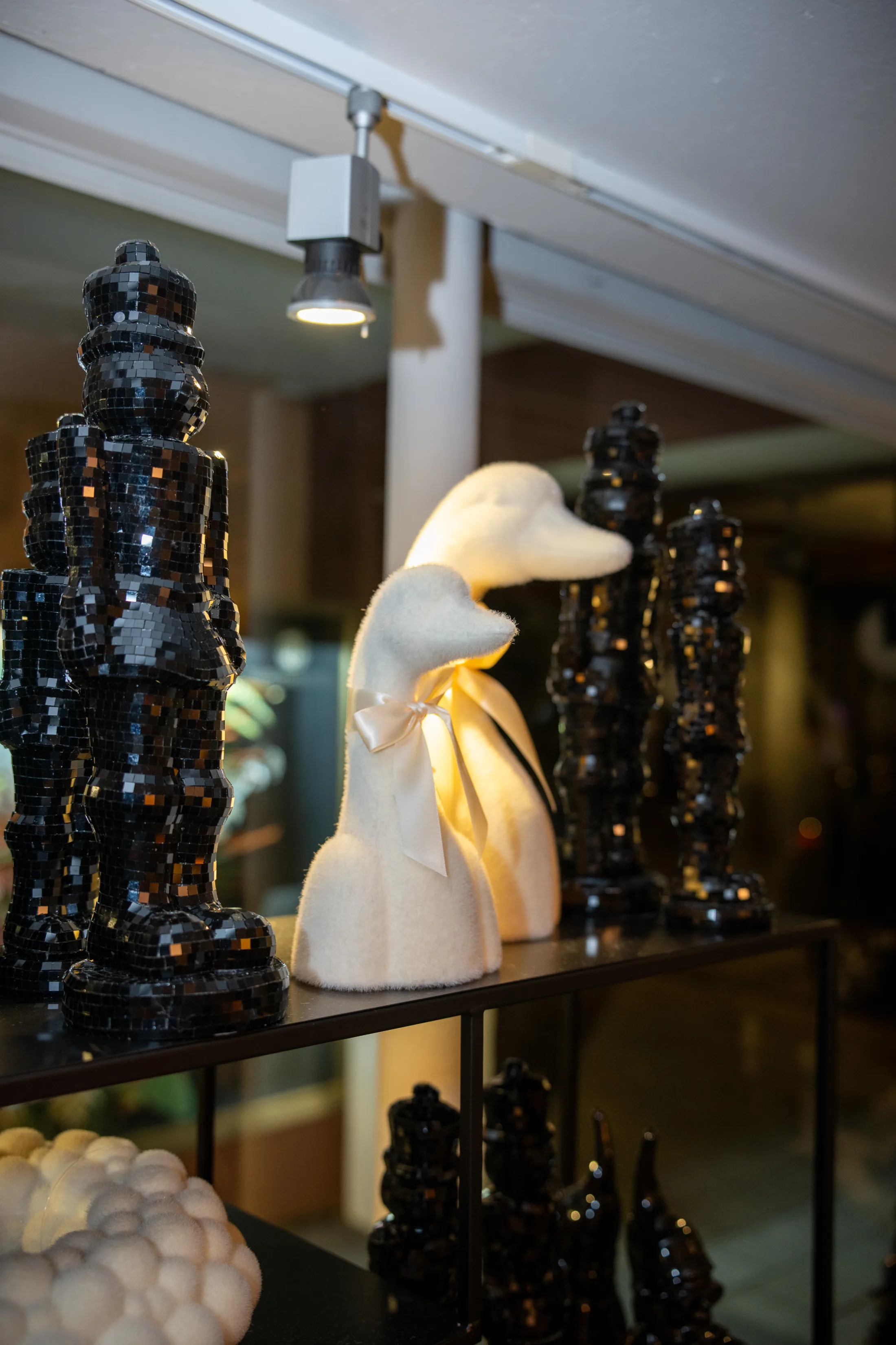 Gans in Creme im Schaufenster neben schwarzen Mosaikfiguren